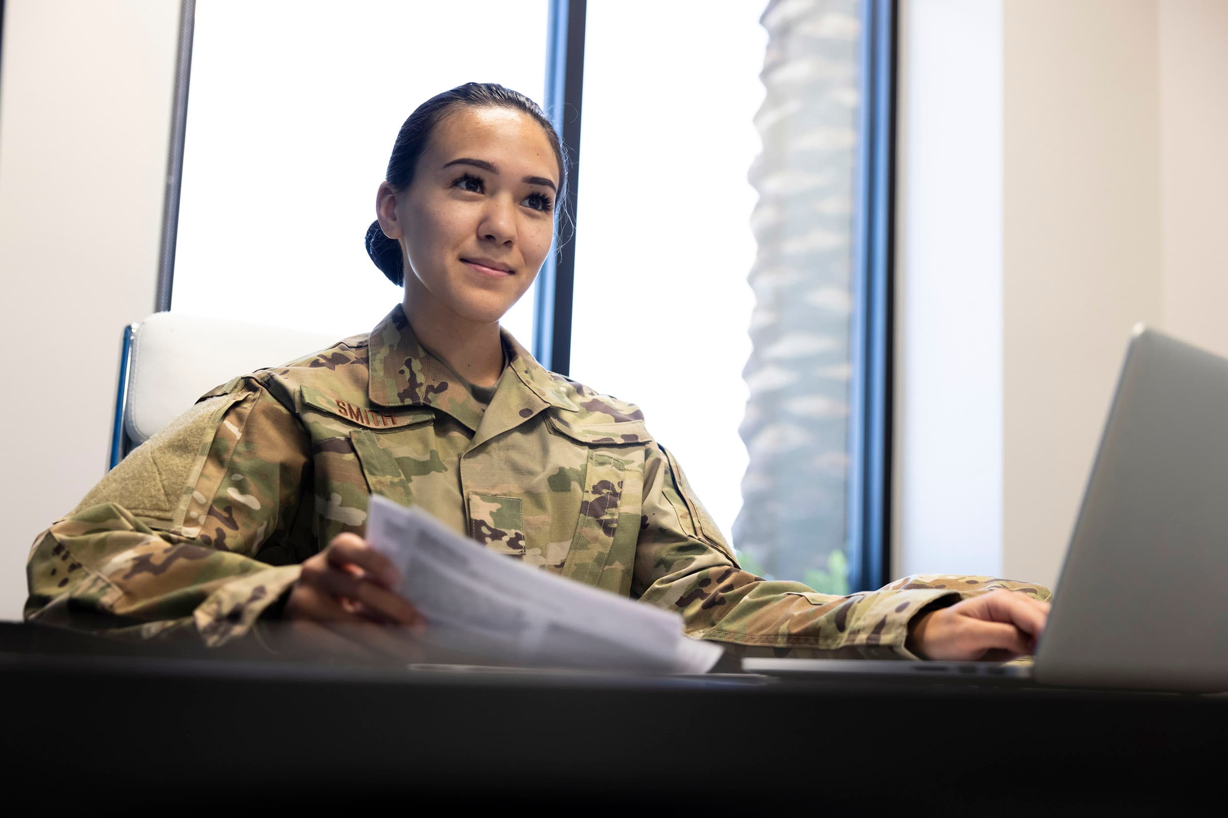 Air Force service member in uniform working at a desk in a civilian office setting, representing the transition from military to civilian careers through the SkillBridge program.