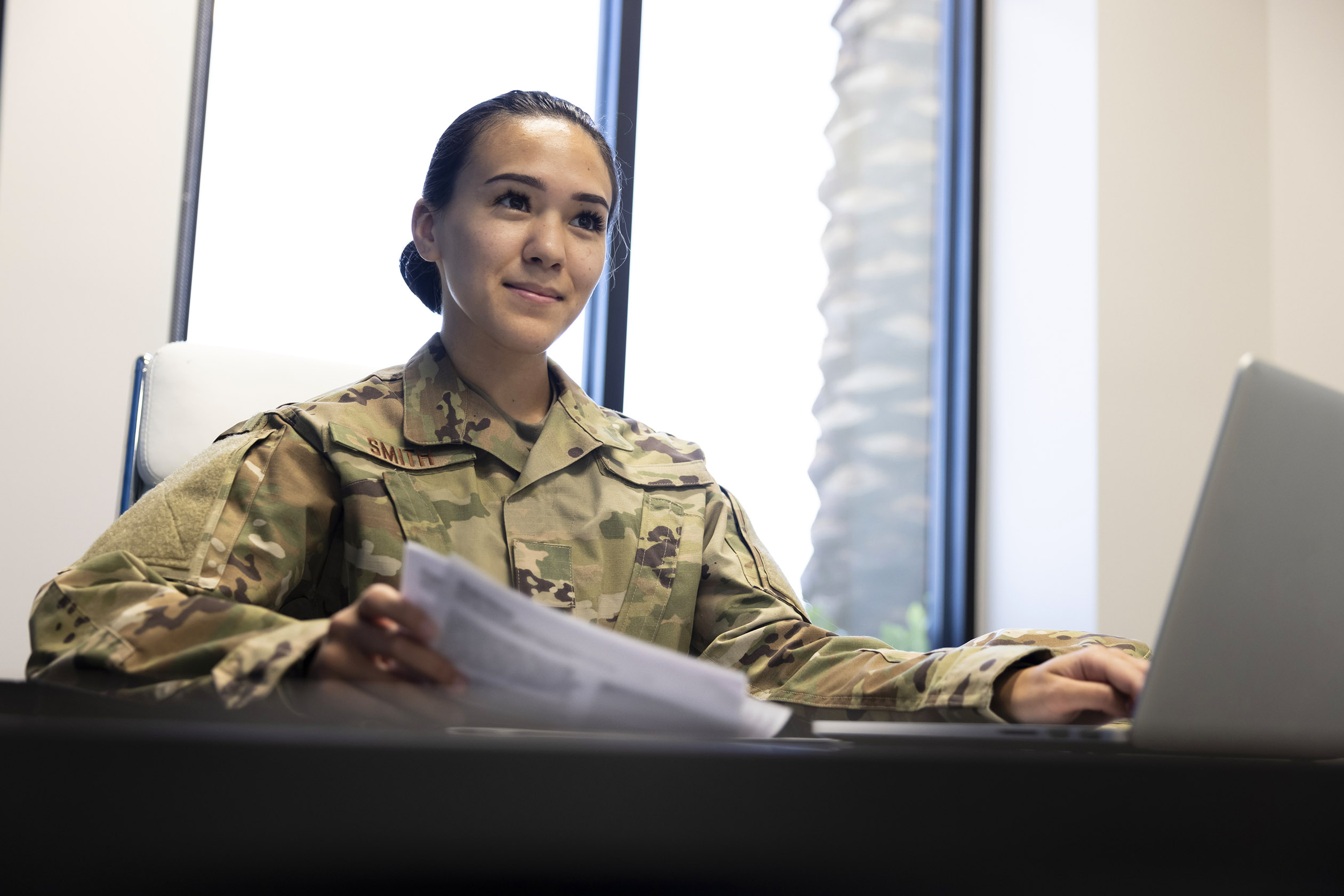 Air Force service member in uniform working at a desk in a civilian office setting, representing the transition from military to civilian careers through the SkillBridge program.